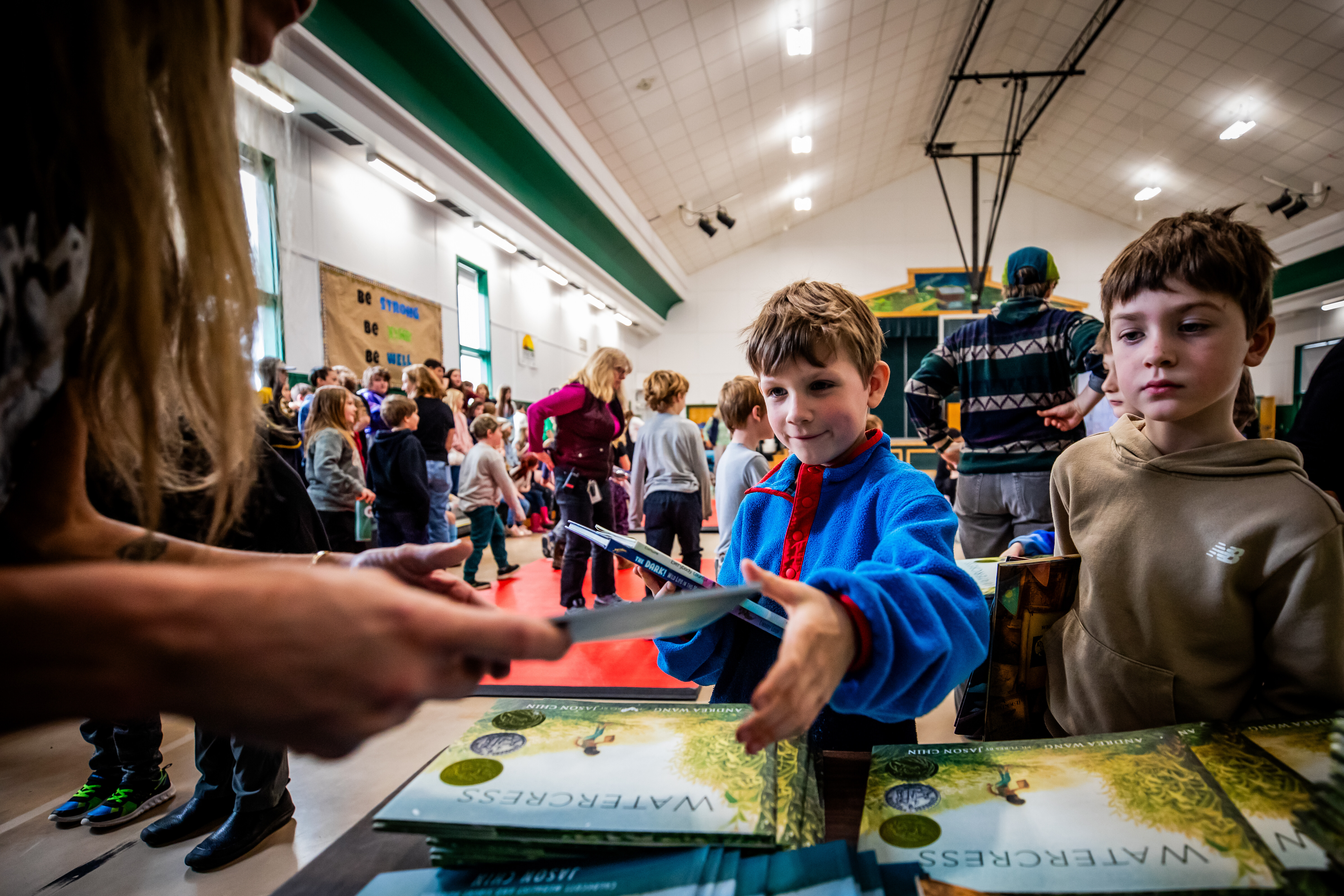 Children at a book signing event, excitedly receiving copies of "Watercress."