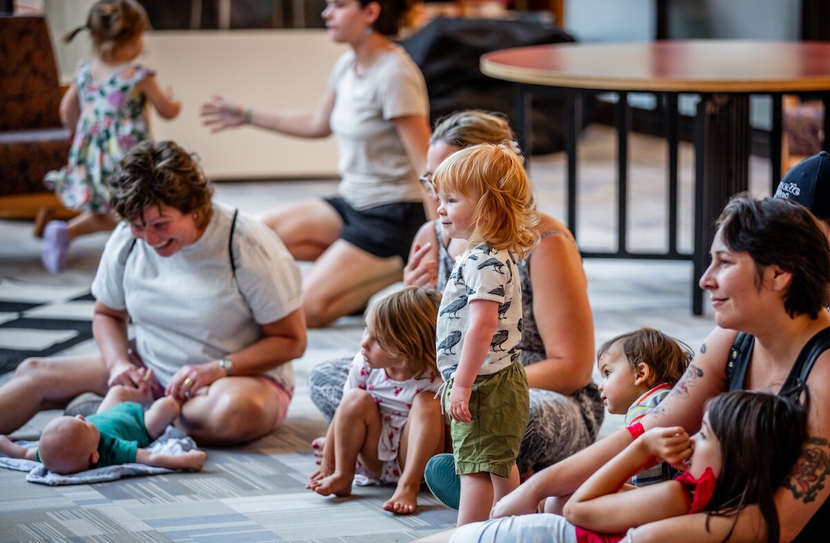A group of parents and children engage in a playful activity on the floor.