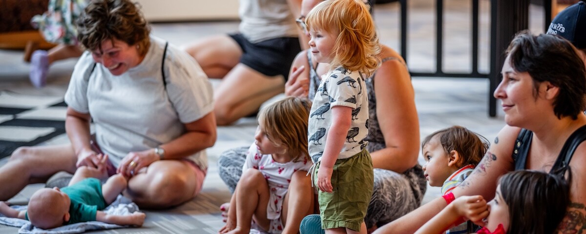 Children and adults sitting together in a playful, engaging environment.