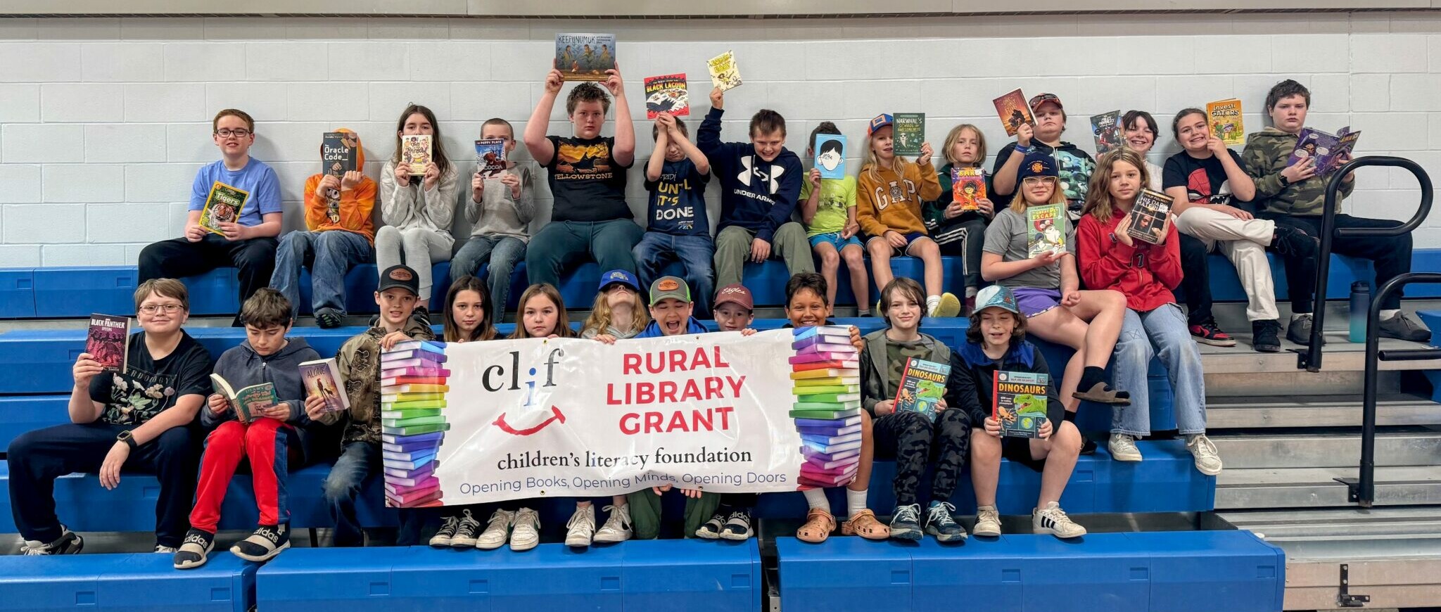 Group of children holding books, posing with a banner for a library grant program.