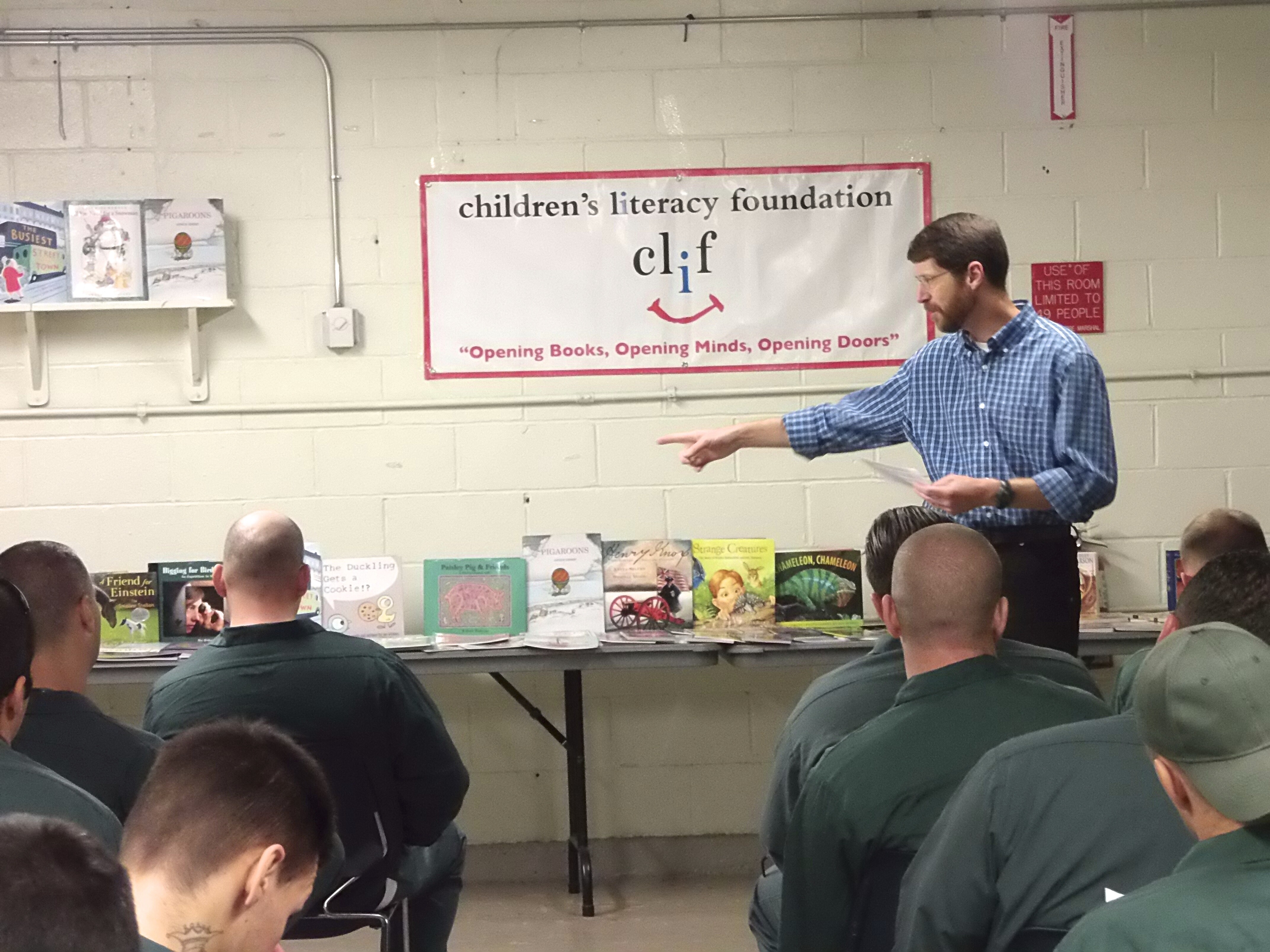 A speaker presents books to an audience in a literacy program setting.