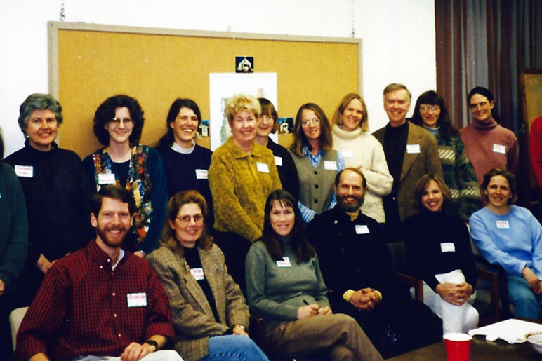 Group photo of diverse people smiling at a gathering, with name tags visible.