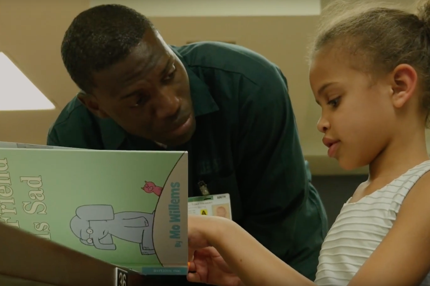 A man and a girl are reading a book together at a table.