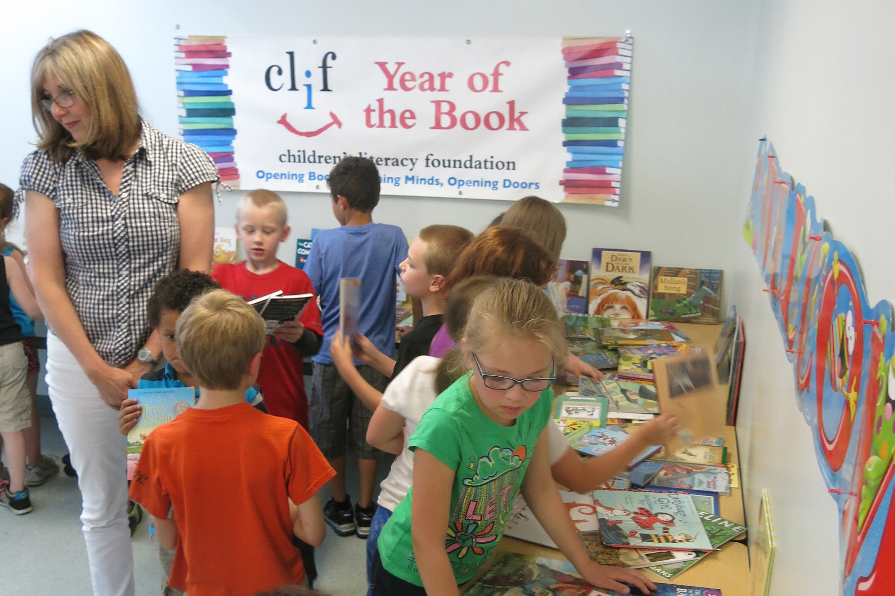 Children explore books at a literacy event, with a banner promoting reading.