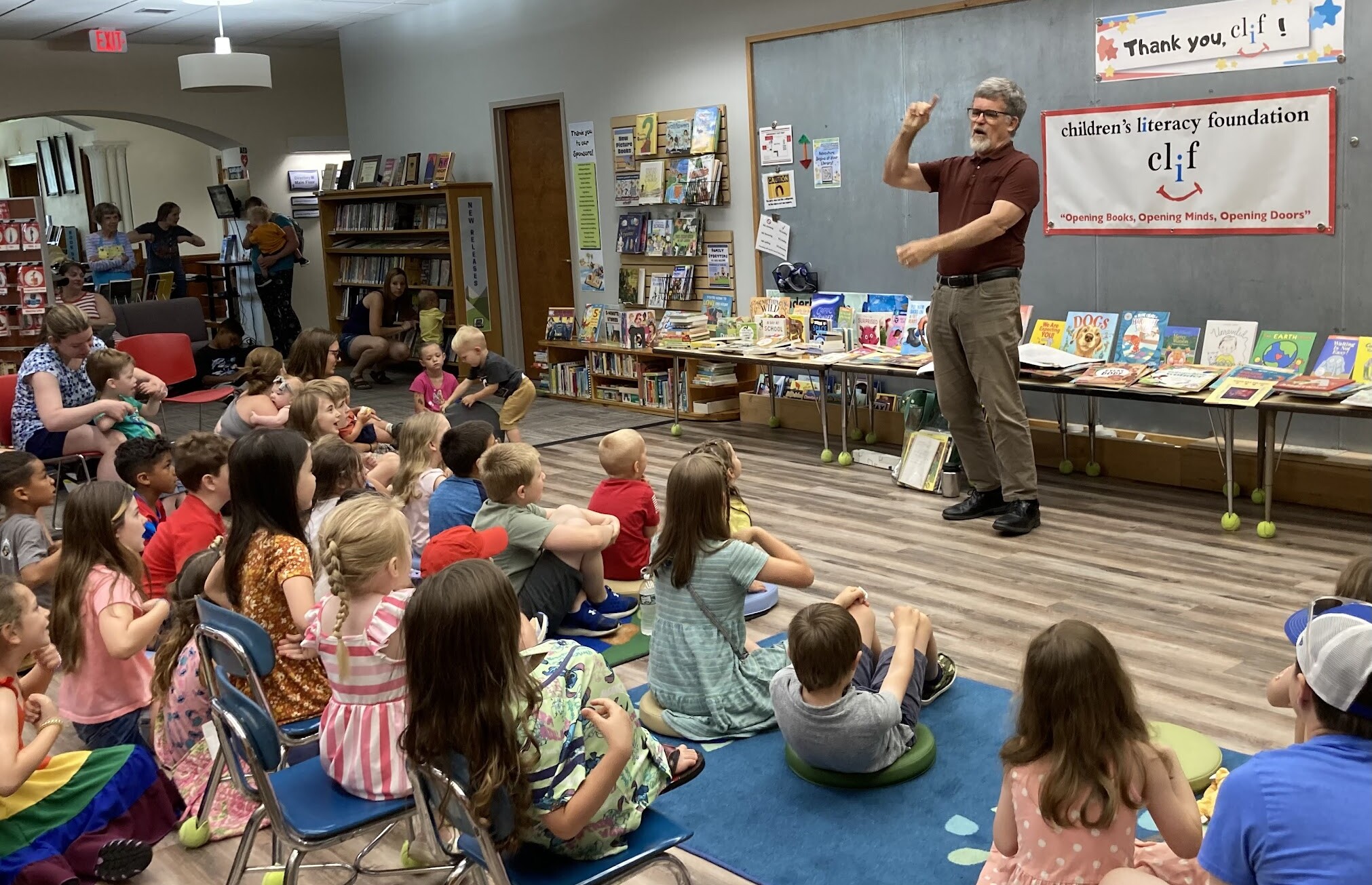 A storyteller engages with children at a library event surrounded by books.