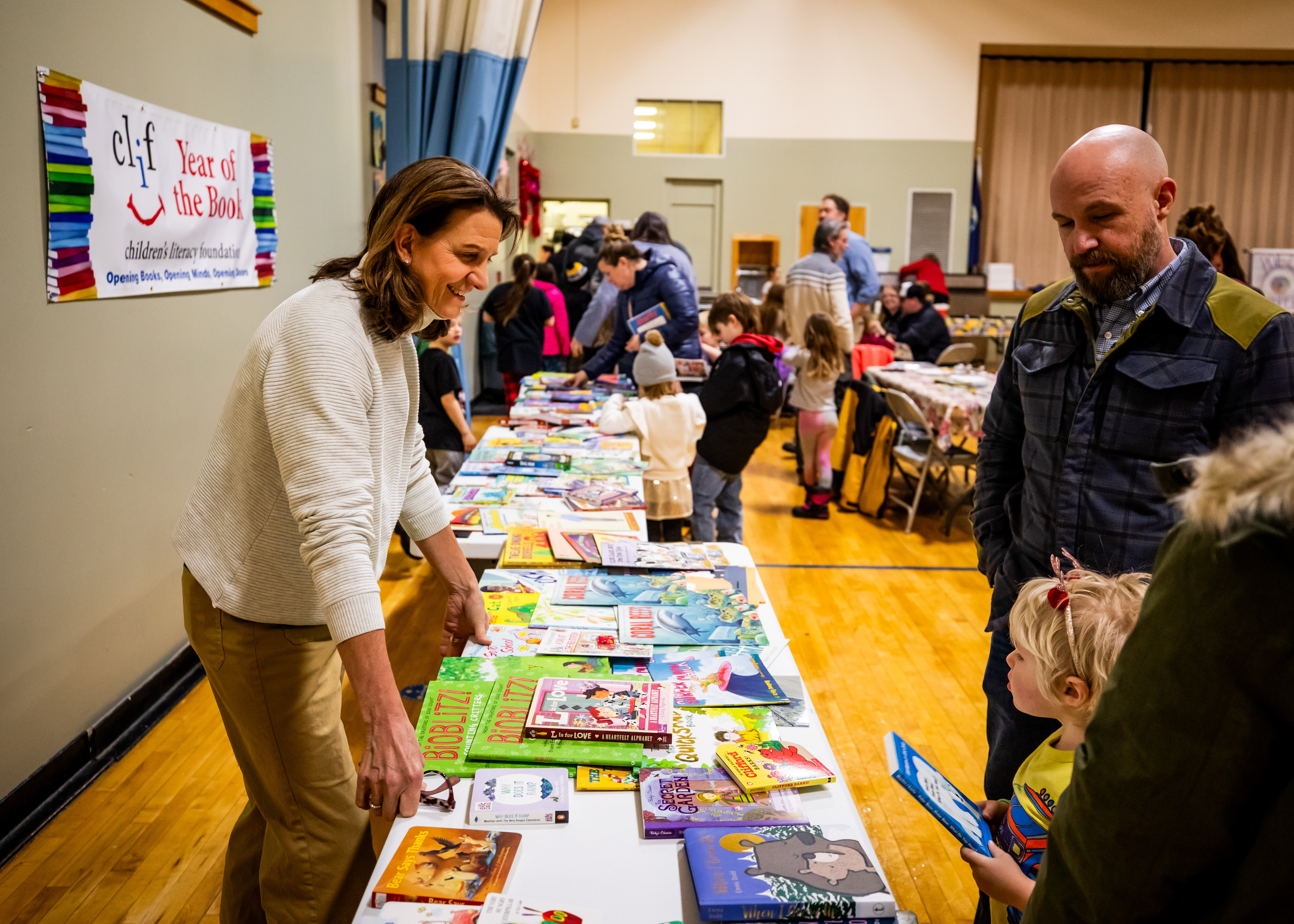 Community event showcasing children's books with families engaging at tables.