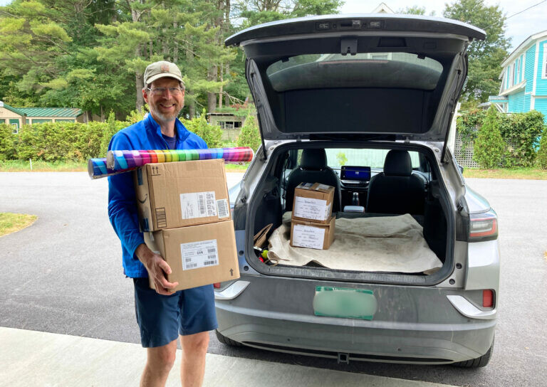 Volunteer loading boxes and supplies into a car for delivery as part of a children&rsquo;s literacy program.