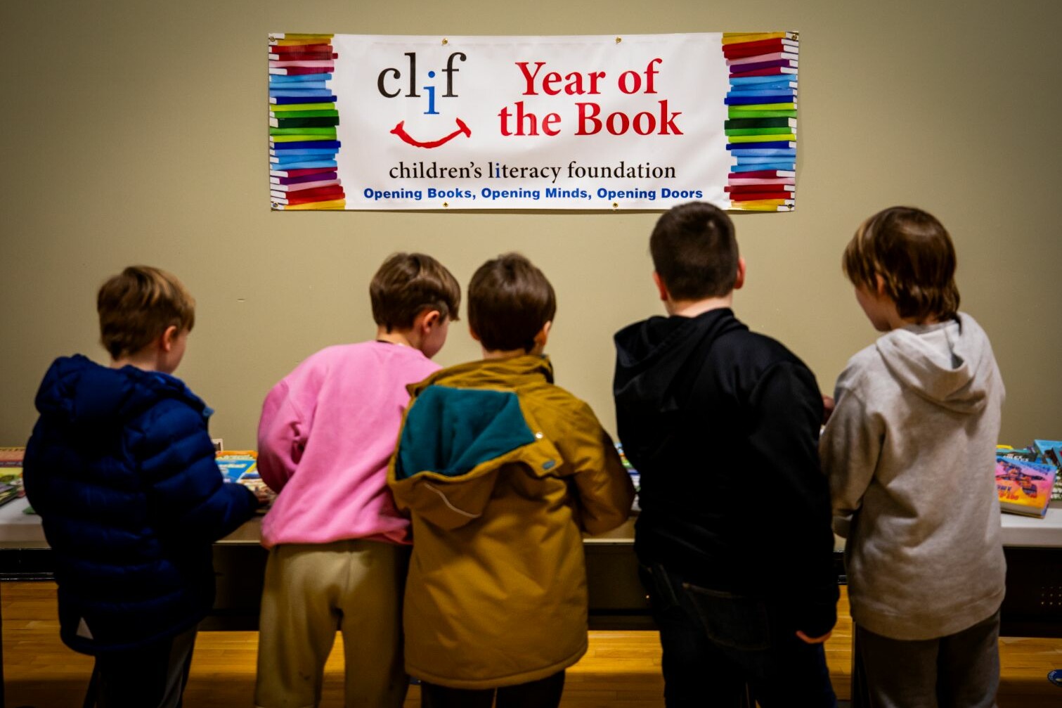 Kids reading at a literacy event themed "Year of the Book" with a colorful banner.