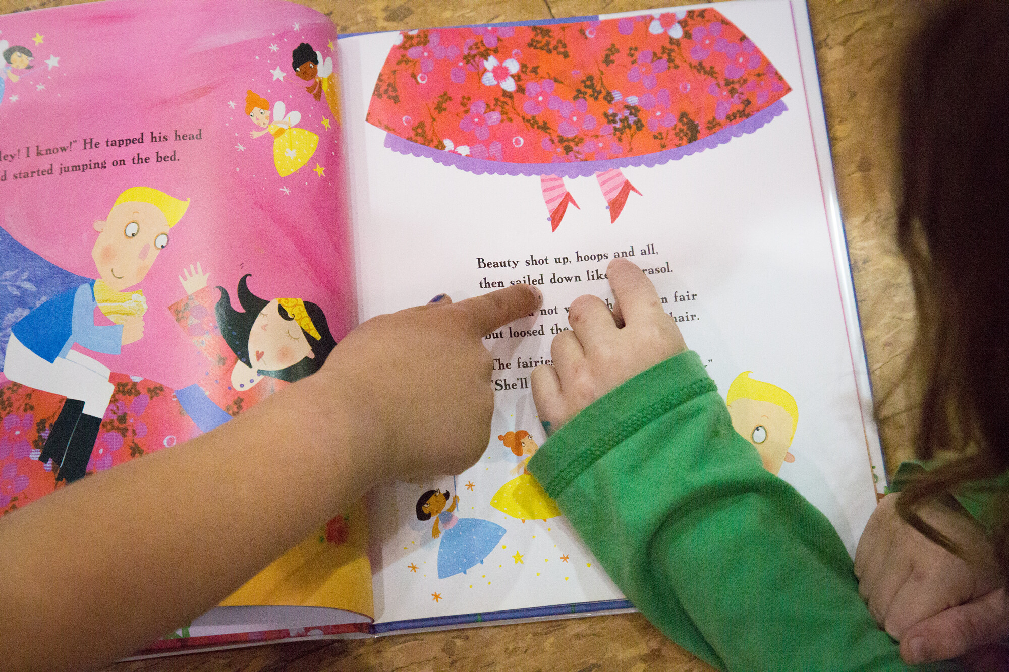 Children point to text in a colorful storybook featuring fairytale illustrations.