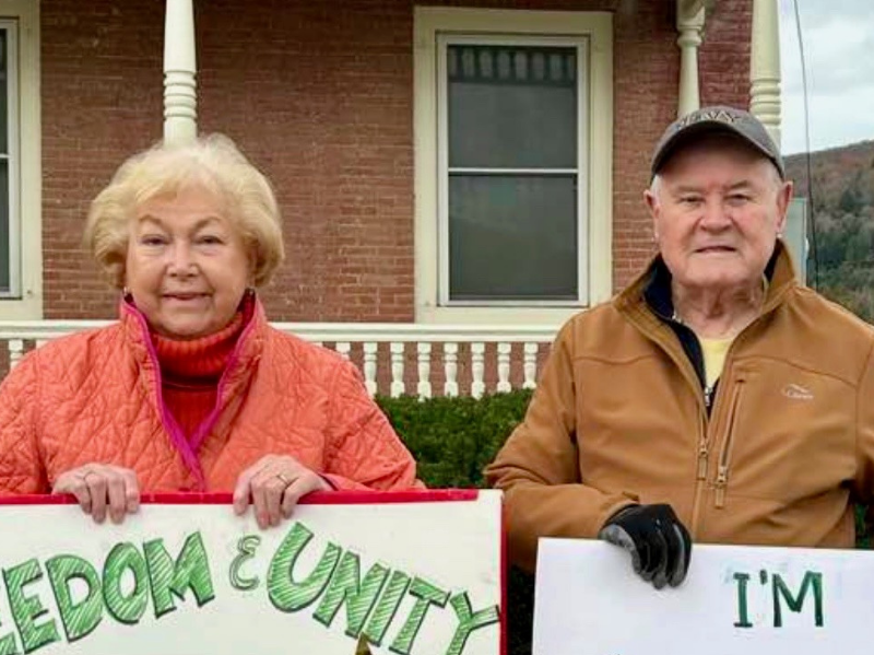 The Luce's holding signs that read "Freedom & Unity" and "I'm" outside a brick building.