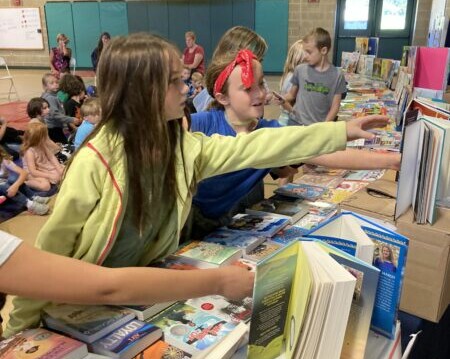 Children selecting new books from a table at a school book distribution event.