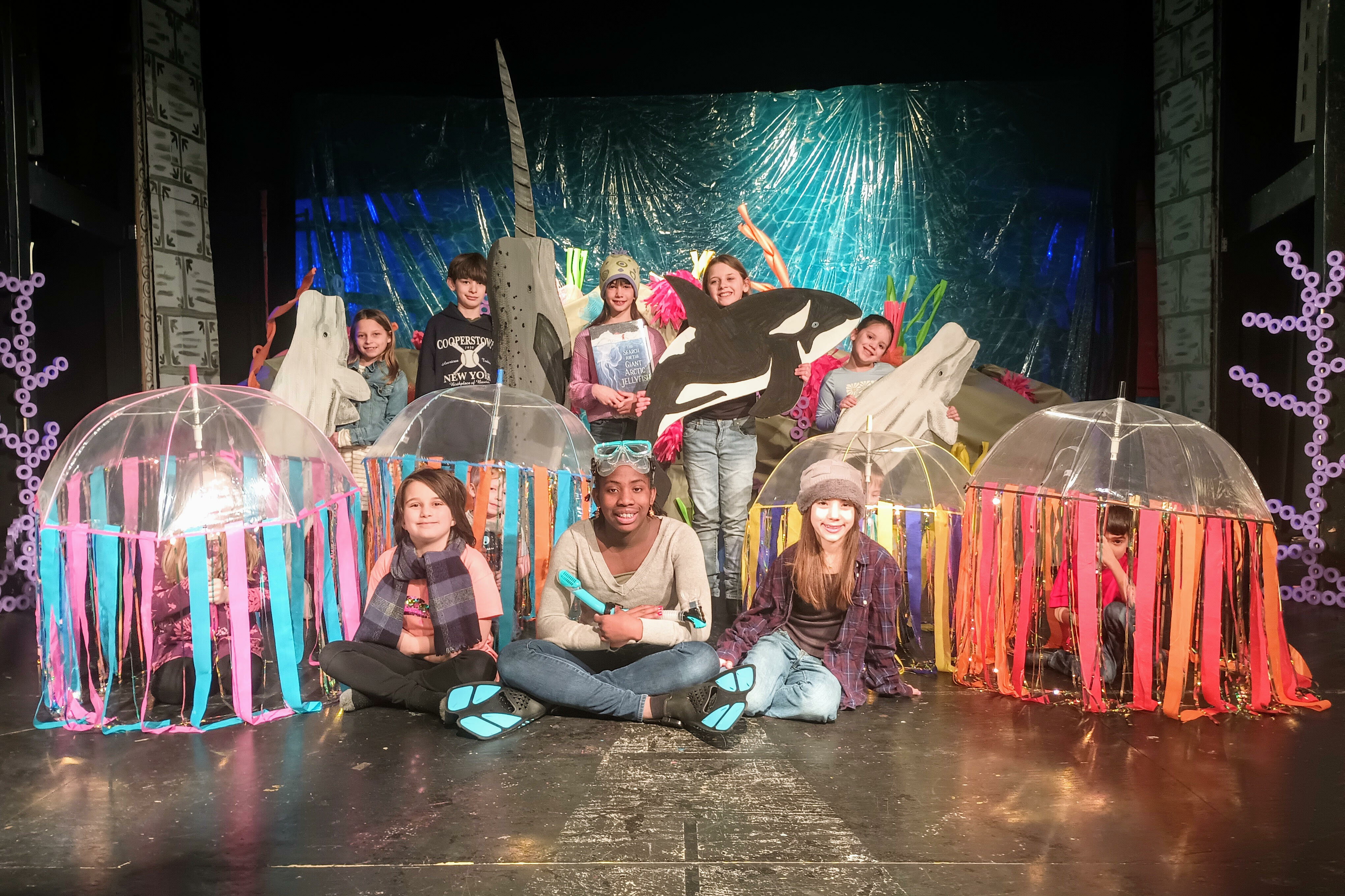 Children performing on stage, surrounded by colorful sea creature props and costumes.