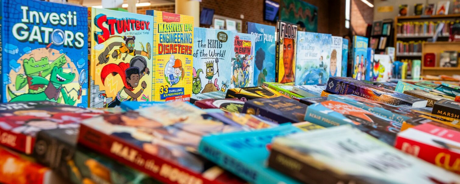 A colorful display of children's books lined up on a table in a library.