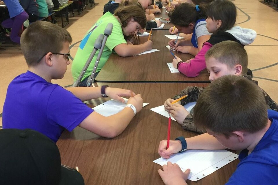 Group of schoolchildren working on a writing assignment while seated at a table