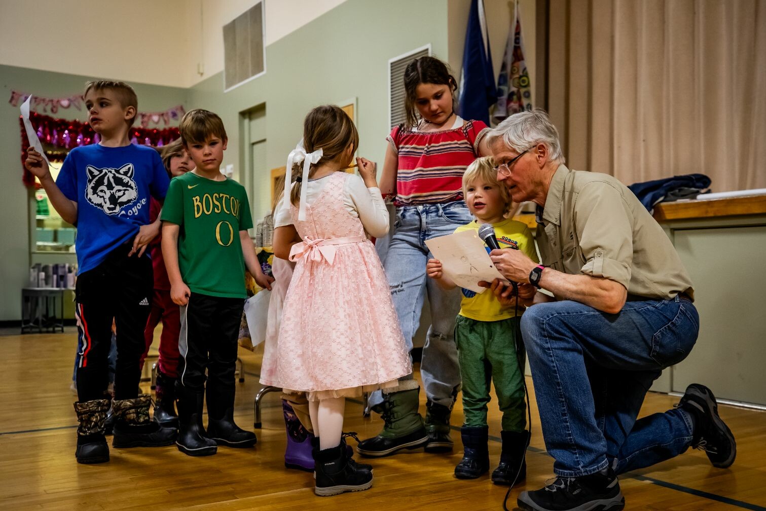 Children participate in an event, taking turns speaking with an adult on stage.