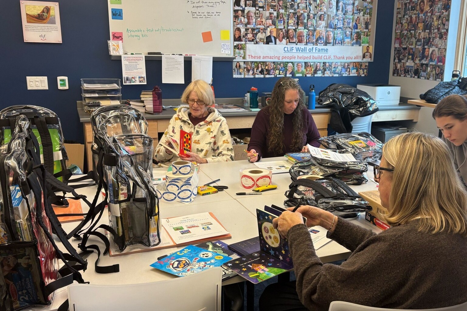 Volunteers assemble educational kits at a collaborative workspace with backpacks and materials.