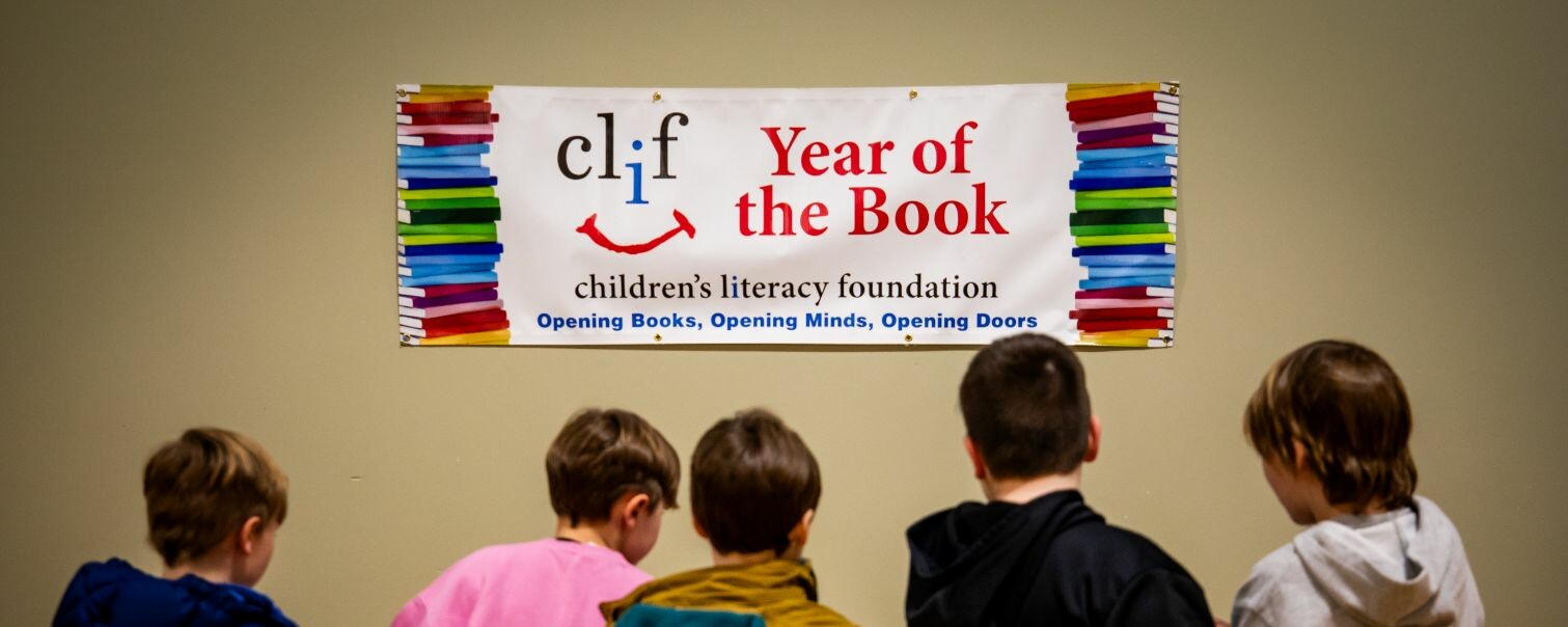 Banner for "Year of the Book" with children facing it, promoting literacy.