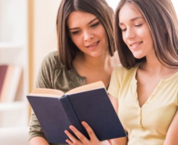 A mentor and student reading a book together, smiling and engaged