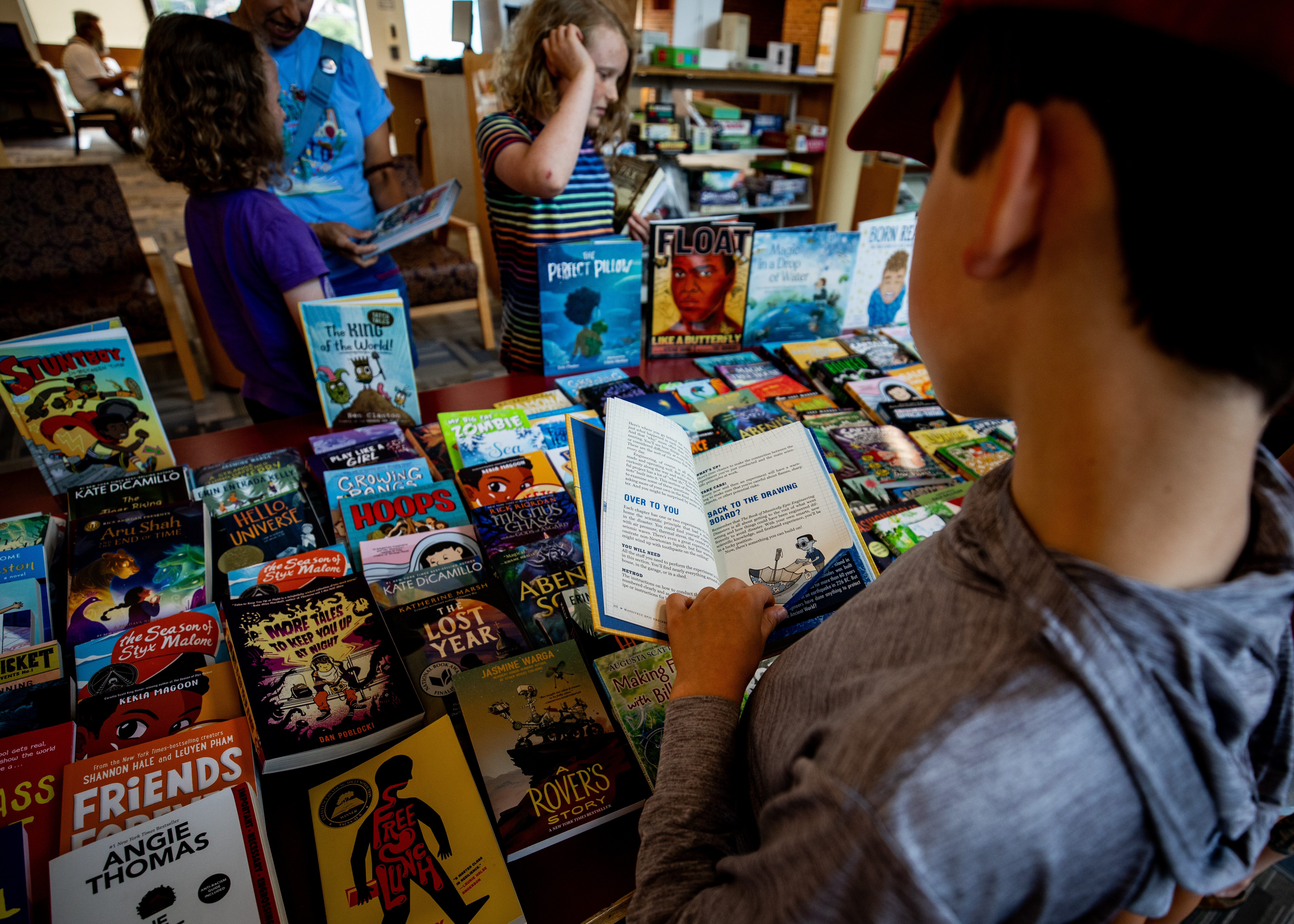 A child browsing a table of colorful books in a library.