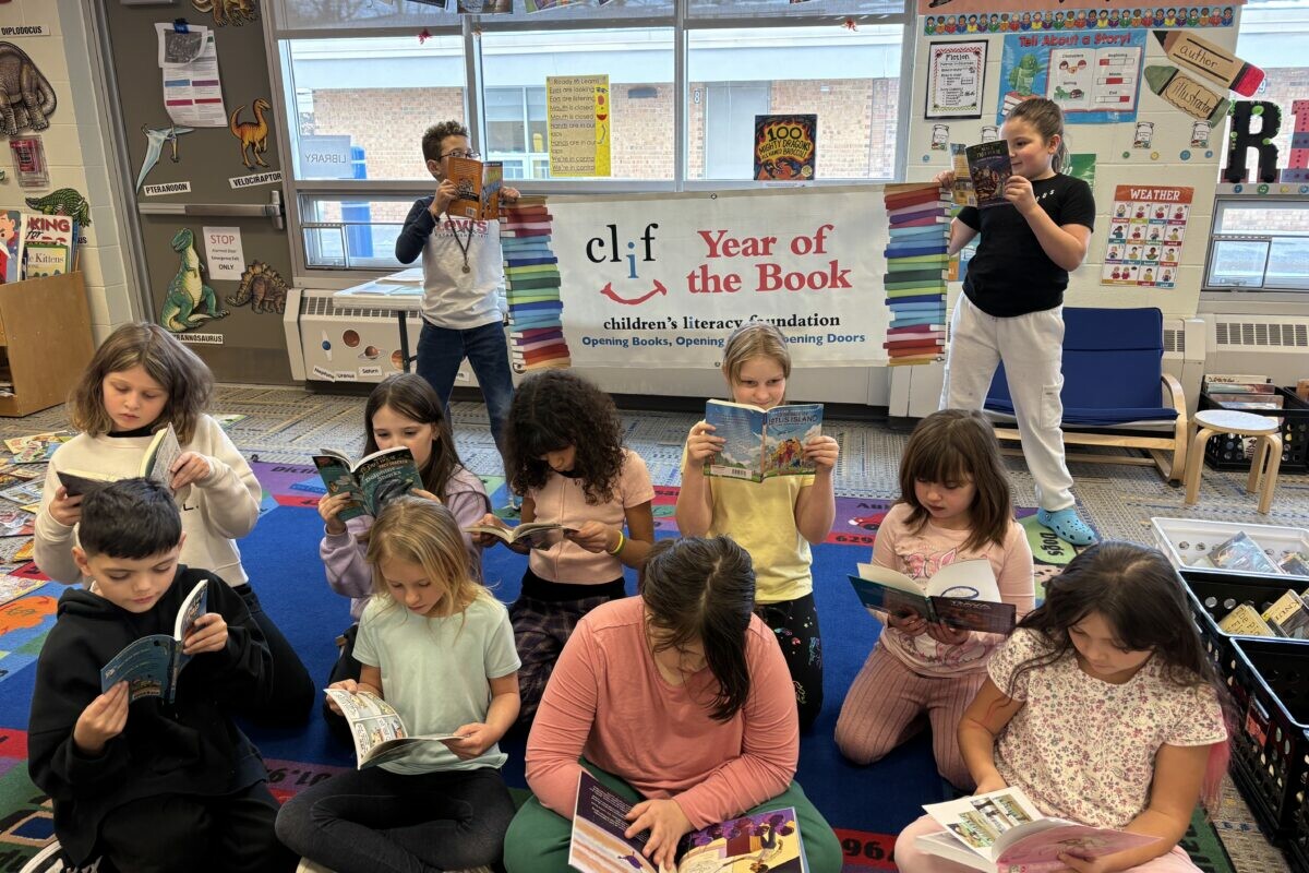 Children reading books in a classroom with a literacy banner in the background.
