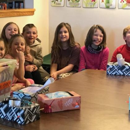 Group of children sitting around a table smiling during a classroom or reading group activity.