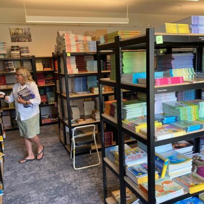 Staff member selecting children’s books from organized warehouse shelving filled with colorful book stacks.