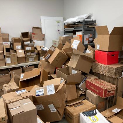 Storage room filled with piles of empty and labeled cardboard shipping boxes used for packing book orders.